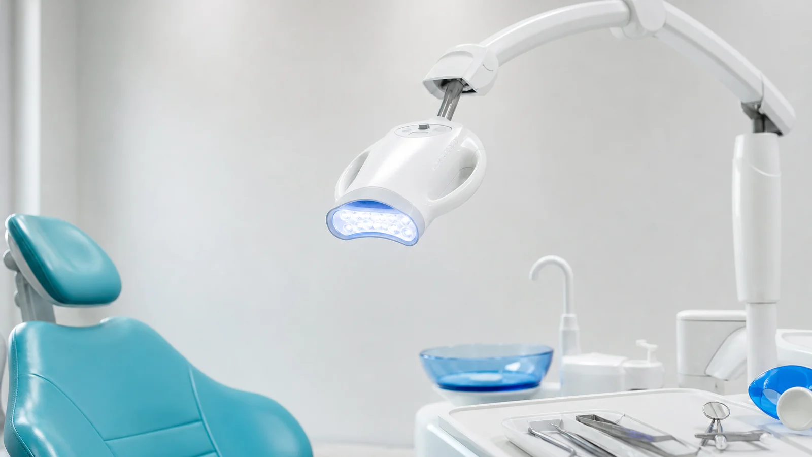 A professional in-office teeth whitening setup with an LED whitening lamp and gel syringes in a modern dental operatory