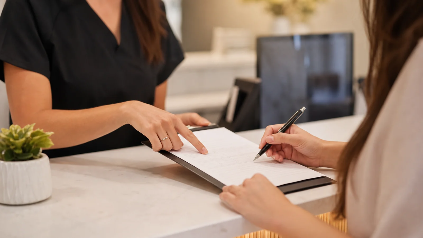 A friendly dental coordinator reviewing paperwork with a patient at a welcoming front desk